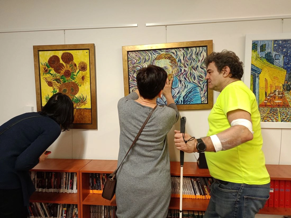 Dłoń osoby odwiedzającej wchodząca w interakcję z interaktywną drewnianą rzeźbą, pokazująca znaczenie fizycznego kontaktu w sztuce.